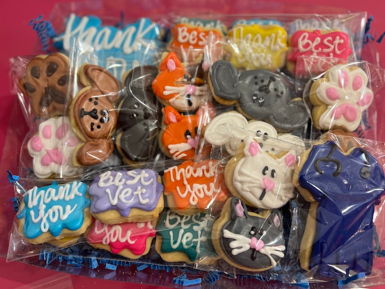 May include: A variety of decorated sugar cookies in a clear plastic bag. The cookies feature animal designs, paw prints, and the text "Thank You" and "Best Vet".