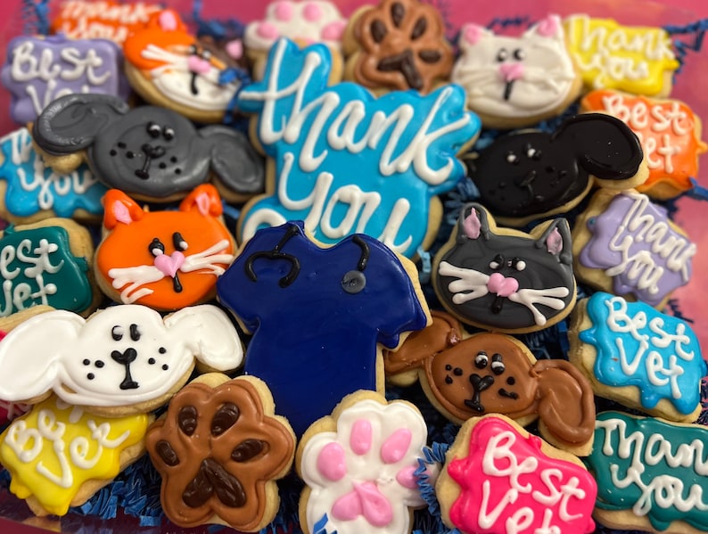 May include: Assortment of decorated sugar cookies with various designs, including paw prints, animals, and the words "Thank You", "Best Vet", and "Best Vet".