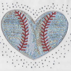 May include: A white fabric background with a heart-shaped design featuring a baseball with red stitching. The heart is surrounded by small silver dots.