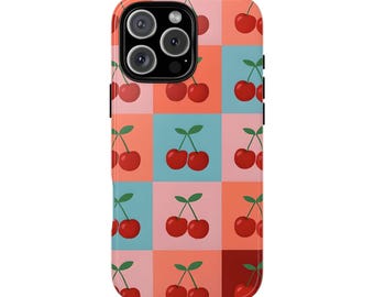 Puede incluir: Funda de teléfono colorida con un patrón repetido de cerezas rojas con tallos verdes sobre un fondo a cuadros de cuadrados rosas, coral y turquesas. La funda tiene un módulo de cámara negro.