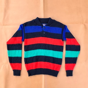 May include: A striped sweater with a mock neck and a button closure. The sweater is black, red, blue, and green.