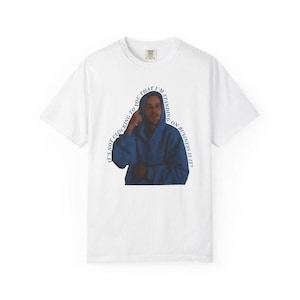 May include: White t-shirt featuring a graphic of a person in a blue hoodie with the text "IT'S NOT CLOCKING TO YOU THAT I'M STANDING ON BUSINESS IS IT?" in a curved font. The shirt has a crew neck and short sleeves.