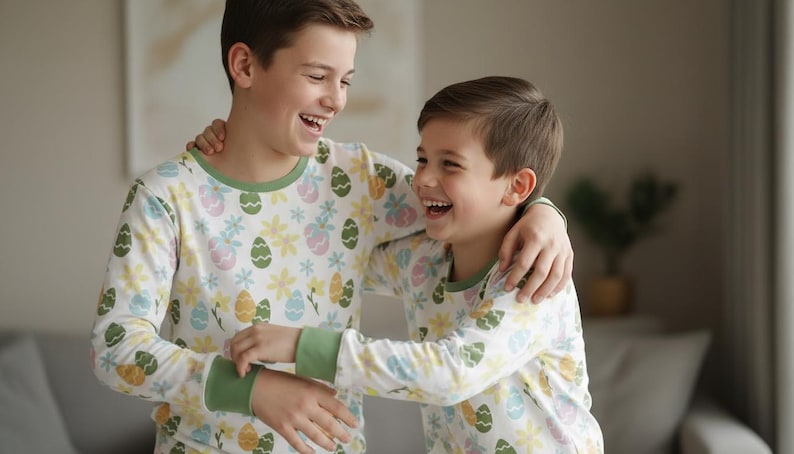 Pu&ograve; includere: Due persone indossano pigiami a maniche lunghe abbinati con un motivo a uova di Pasqua e floreale. I pigiami hanno finiture verdi sul colletto e sui polsini. Entrambe le persone sorridono e si abbracciano.