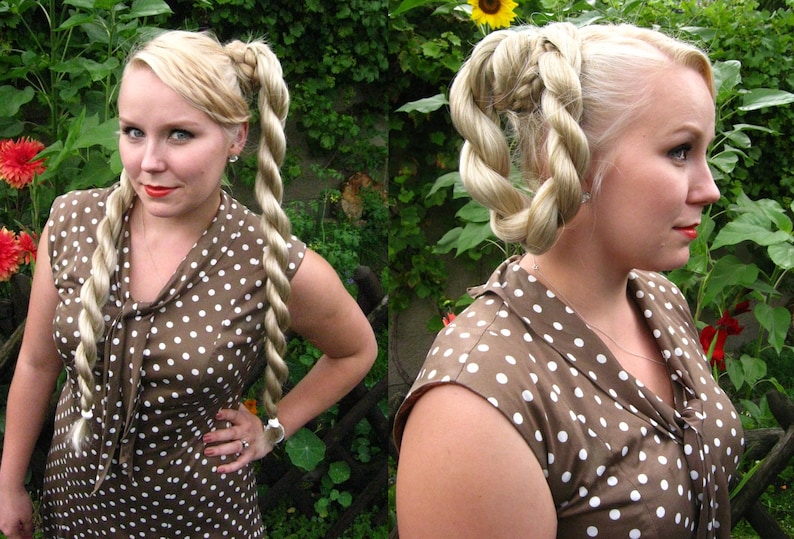 May include: A woman with blonde hair styled in two braided rope twists, wearing a brown dress with white polka dots.