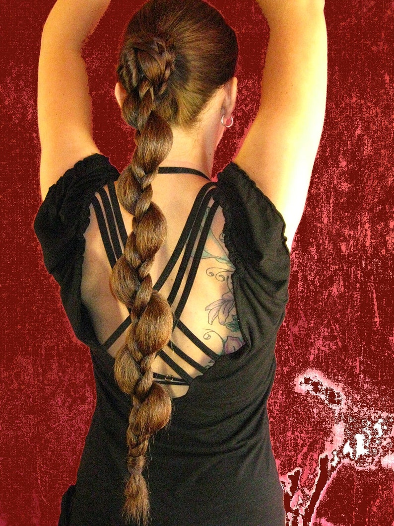 Op de afbeelding: Een vrouw met lang bruin haar dat in een gevlochten paardenstaart is gestyled. Ze draagt een zwart, mouwloos topje met een gekruiste rug.