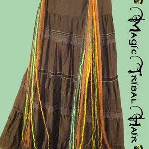 May include: A brown skirt with multiple tiers and lace trim. Two gold flower-shaped clips are attached to the skirt, each with colorful yarn strands hanging down.