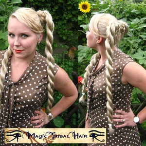 May include: A woman with blonde hair styled in two long, thick braids. She is wearing a brown and white polka dot dress. The dress has a V-neck and short sleeves. The woman is standing in a garden with green plants and flowers.