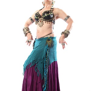 May include: A woman wearing a black and gold bra with a peacock feather accent, a turquoise and purple skirt, and multiple silver bracelets on both wrists.