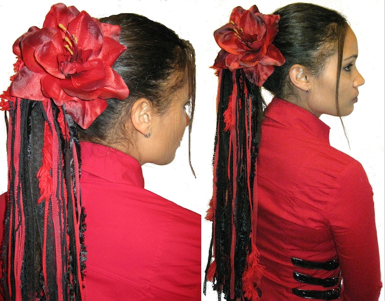 May include: A red fabric flower hair clip with black and red fabric strands hanging down. The flower is attached to a black elastic band.