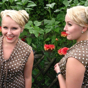 May include: Two women with blonde hair wearing brown and white polka dot dresses. The women are standing in front of a green leafy background.