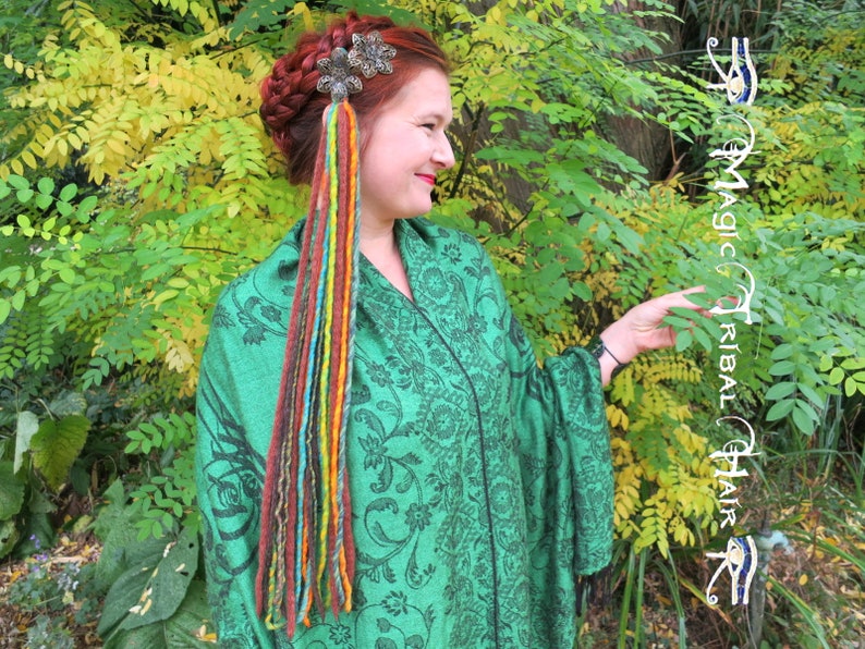 May include: A woman with a braid in her hair wears a green shawl with a floral pattern. She has a silver hair clip with a colorful yarn braid hanging from it.