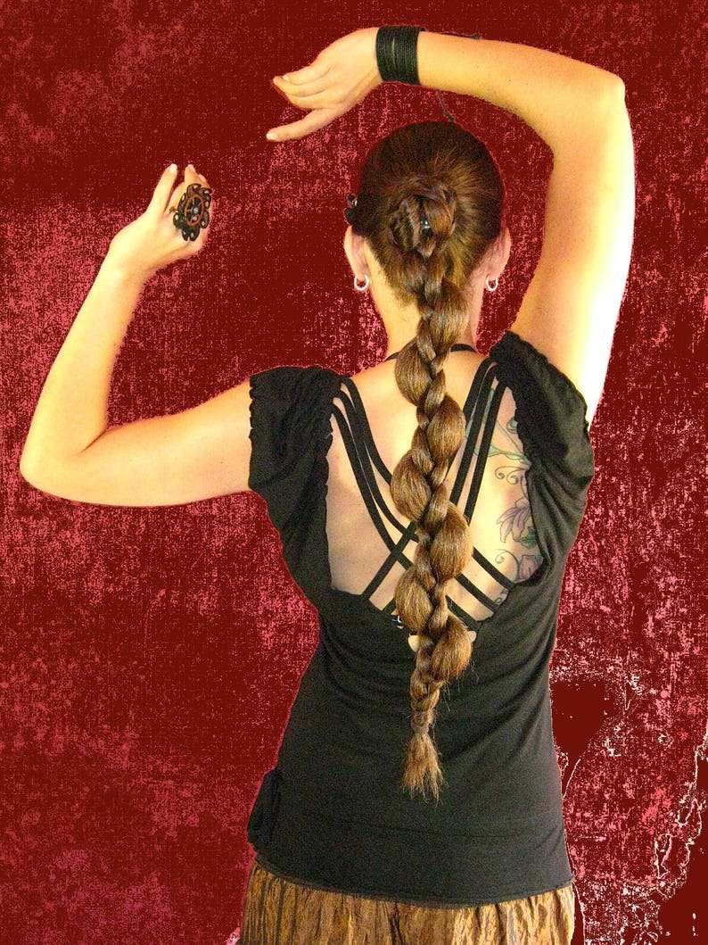 Op de afbeelding: Een vrouw met lang bruin haar dat in een gevlochten paardenstaart is gestyled, draagt een zwart, mouwloos topje met een kruisrugontwerp en een bruine rok.