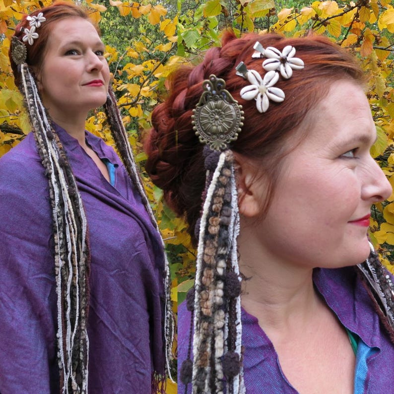 K&ouml;nnte beinhalten: Eine Frau mit roten Haaren tr&auml;gt ein lilafarbenes Hemd und hat verschiedene Haarschmuck in ihren Haaren. Zu den Accessoires geh&ouml;ren wei&szlig;e Blumen, ein Metallanh&auml;nger und lange Garnstr&auml;hnen.