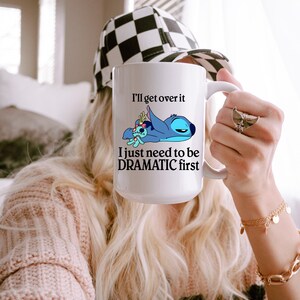 A person holding a mug with a cartoon character and text on it.