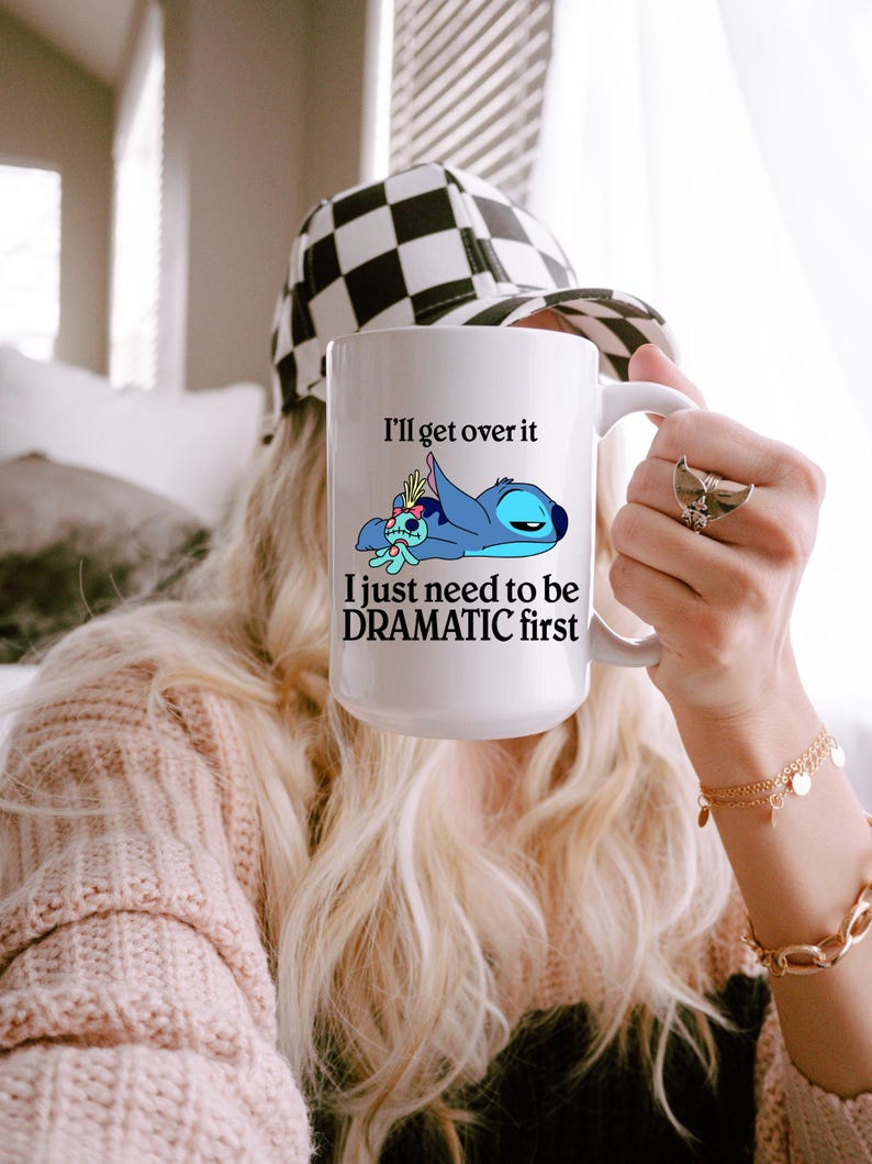 A person holding a mug with a cartoon character and text on it.