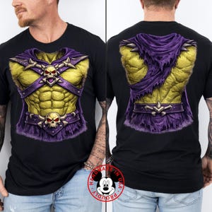 May include: Black t-shirt featuring a graphic design of a muscular torso with a purple and gold armor design. The front and back of the shirt are shown. The design includes skulls and a cape.