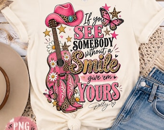 Könnte beinhalten: Ein cremefarbenes T-Shirt mit einem Grafikdesign, das einen rosa Cowboyhut, eine rosa Akustikgitarre und rosa Cowboystiefel zeigt. Der Text lautet, If you SEE SOMEBODY without a Smile give 'em YOURS, ergänzt durch Schmetterlinge und Sterne.
