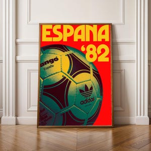 May include: A framed poster featuring a soccer ball design. The poster has a red background with the word "ESPAÑA" in yellow, along with the number "'82". The soccer ball is green and yellow with the Adidas logo.