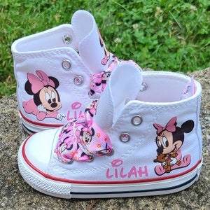 May include: White high-top sneakers with pink Minnie Mouse characters and a pink bow. The shoes are personalized with the name "Lilah".
