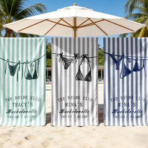 May include: Three rectangular beach towels with vertical stripes in mint green, grey, and navy blue. Each towel features a graphic of bikinis hanging on a clothesline and the text THE BRIDE CLUB, a name, Bachelorette, and CAPE COD | AUG 2026.