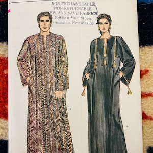 May include: Very Easy Vogue sewing pattern featuring illustrations of two long dresses. One dress is patterned in brown and gold chevrons, the other is black with gold trim and tassels. Text includes "ALL SIZES INCLUDED".