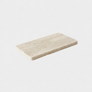 May include: A rectangular, light beige stone serving board with a textured surface. The board has rounded edges and a natural, earthy appearance, suitable for displaying food or decorative items.
