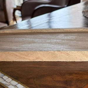 Pu&ograve; includere: Un vassoio in legno di forma ovale con una finitura color marrone chiaro e venature naturali del legno. Il vassoio presenta un centro poco profondo e un bordo liscio e arrotondato, offrendo un design semplice per riporre piccoli oggetti.