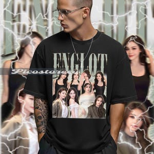 May include: Black t-shirt with a graphic of several women and the word "ENGLOT" in a distressed font. The shirt is worn by a person with glasses and a silver chain. The background has a blurred effect with lightning bolts.