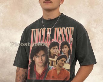 May include: A charcoal gray short-sleeve t-shirt featuring a graphic print of the text UNCLE JESSE in a bold orange font above a collage of four photographs of the same person with dark hair, wearing various shirts and a leather vest.