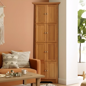 May include: A tall, light brown wooden corner cabinet featuring four stacked sections, each with two vertical paneled doors and small, round silver-toned knobs. The unit is designed to fit into a corner and has a flat top molding.