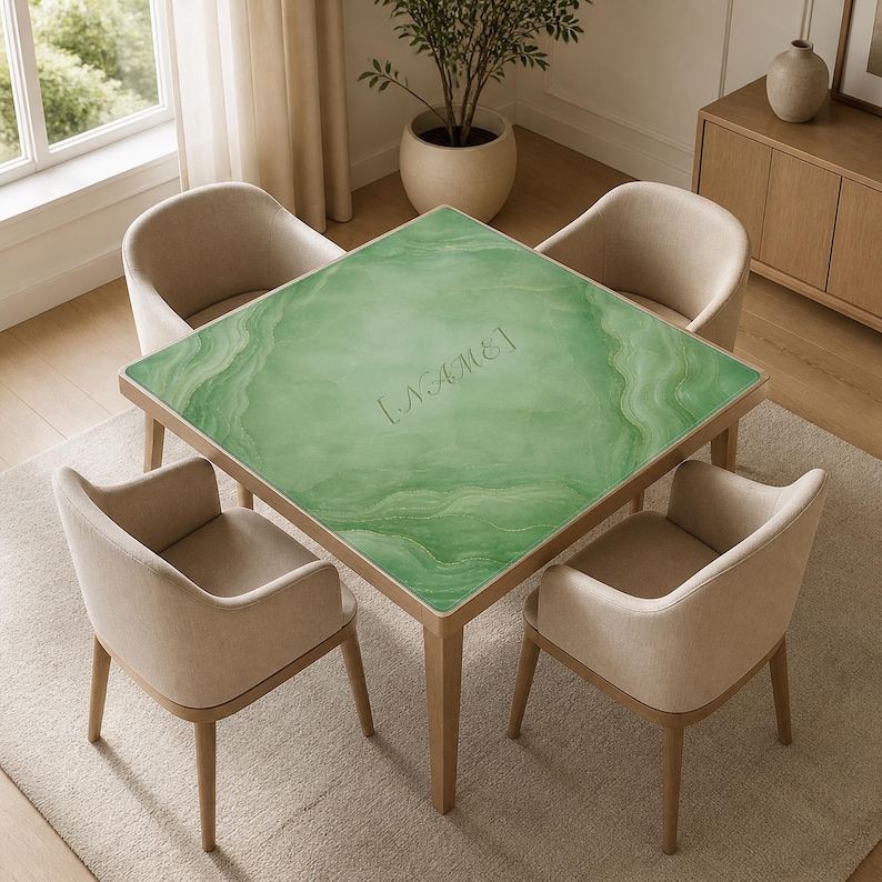 May include: A square dining table with a green marble-like top and wooden legs, surrounded by four beige upholstered chairs. The table's surface features a swirling pattern and the word "NAME" is etched into the surface.