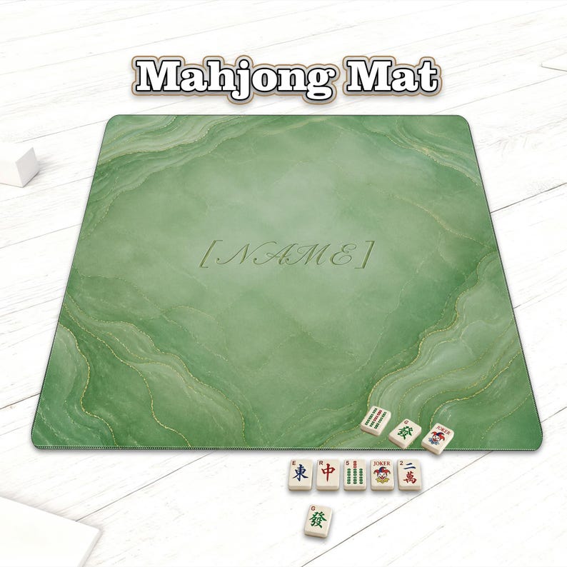 May include: A green Mahjong mat with a marble-like design and the text "Mahjong Mat" at the top. The mat has the word "[NAME]" in the center. Several Mahjong tiles are arranged on the surface.