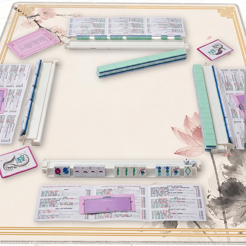 May include: A complete Mahjong set with a cream-colored playing surface featuring floral and botanical designs. The set includes tiles, racks, and score cards. The tiles are primarily green and white, with some tiles displaying colorful symbols.