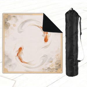 May include: A square yoga mat featuring a koi fish design in shades of orange, white, and gray. The mat has a gold border and a black underside. A black carrying bag with a shoulder strap is also included.