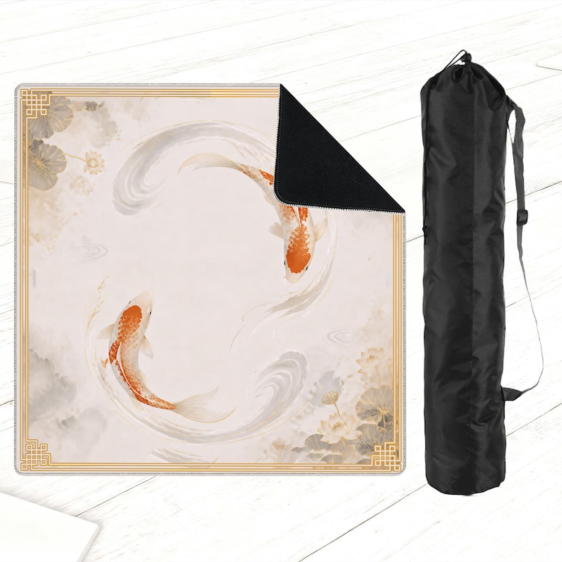 May include: A square yoga mat featuring a koi fish design in shades of orange, white, and gray. The mat has a gold border and a black underside. A black carrying bag with a shoulder strap is also included.