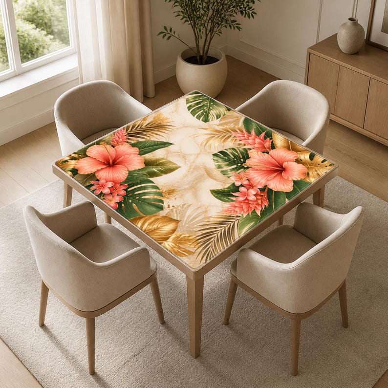 K&ouml;nnte beinhalten: Ein quadratischer Esstisch mit floralem Design, das gro&szlig;e korallenfarbene Hibiskusbl&uuml;ten, gr&uuml;ne Bl&auml;tter und goldene Akzente aufweist. Der Tisch ist von vier beige gepolsterten St&uuml;hlen umgeben. Der Tisch misst ca. 91 cm x 91 cm.