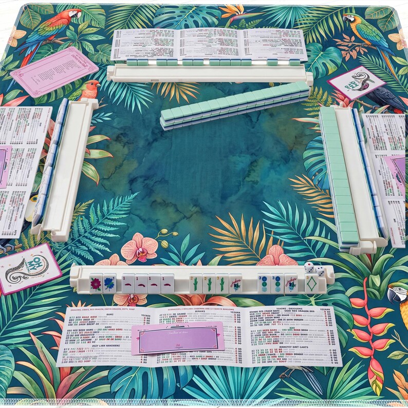 May include: A Mahjong set with white and green tiles, dice, and scorecards, arranged on a tropical-themed mat with parrots and floral patterns. The set includes racks and a variety of tiles for gameplay.