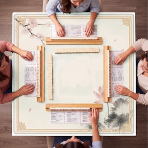 May include: A square Mahjong game table with a floral design and four players. The table features a cream-colored surface with a border of gold geometric patterns. Cherry blossom branches and lotus flowers decorate the table. Wooden racks hold tiles, and each player has a game sheet.