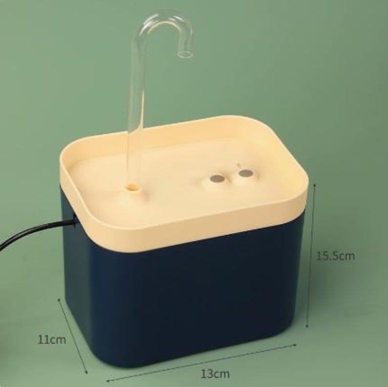 May include: A blue and cream-colored pet water fountain. The fountain has a clear, curved spout and measures approximately 5.1 inches tall, 4.3 inches wide, and 6.1 inches long.