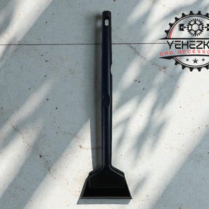 May include: A black ice scraper with a long handle and a rectangular blade. The scraper has a hole at the top of the handle. The logo "YEHEZKEL CAR ACCESSORIES" is visible in the upper right corner.
