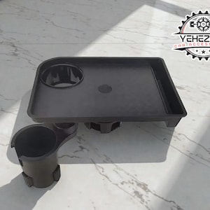 Könnte beinhalten: Ein schwarzes Autozubehör-Tablett mit zwei Getränkehaltern und einem kleinen Tablettbereich. Das Tablett besteht aus Kunststoff und hat eine matte Oberfläche. Das Logo "YEHEZKEL CAR ACCESSORIES" ist rechts oben sichtbar.