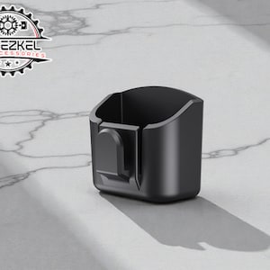 Könnte beinhalten: Ein schwarzer Getränkehalter für Autozubehör mit Clip. Der Getränkehalter besteht aus mattschwarzem Material und hat ein geschwungenes Design. Das Logo "YEHEZKEL CAR ACCESSORIES" befindet sich oben links.