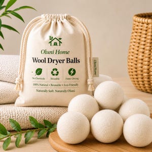 May include: A set of off-white wool dryer balls arranged in front of a cream-coloured drawstring storage bag. The bag features the text Oluni Home, Wool Dryer Balls, and icons representing no chemicals, reusable, and faster drying features.