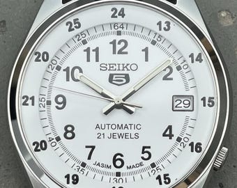 Reloj automático Seiko 5 con esfera blanca y correa de piel de zorro negra de 17 joyas.
