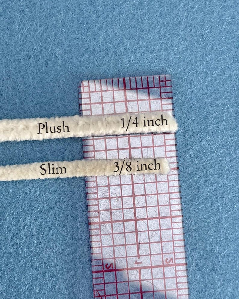 May include: Two beige pipe cleaners are shown against a light blue background, one labelled "Plush" and measuring 0.64 cm, the other "Slim" at 0.95 cm. A clear ruler with red grid lines is positioned next to the pipe cleaners.