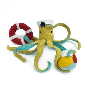 May include: A yellow felt octopus wearing a blue and white sailor hat, holding a red and white life preserver and a yellow, blue and red beach ball.
