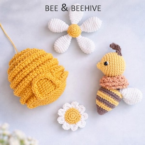 May include: A collection of crocheted items including a yellow beehive, a bee with brown and yellow stripes, and two white and yellow daisies. The text "BEE & BEEHIVE" is at the top.