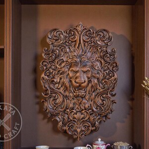 a large, intricately carved wooden lion head mounted on a wall, surrounded by various decorative elements such as a vase of flowers and a book.