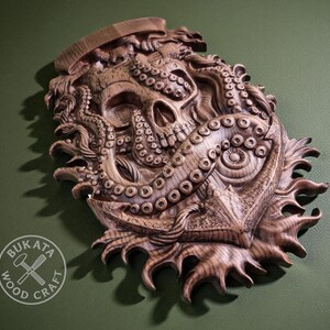 a wooden sculpture of an octopus with a skull-like face, set against a green background.
