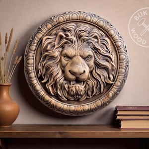 Op de afbeelding: Een gedetailleerd, rond houten wandreliëf met een leeuwenkop met een felle uitdrukking. Het reliëf is in bruin- en beigetinten. De afbeelding bevat een vaas met gedroogde planten en een stapel boeken.